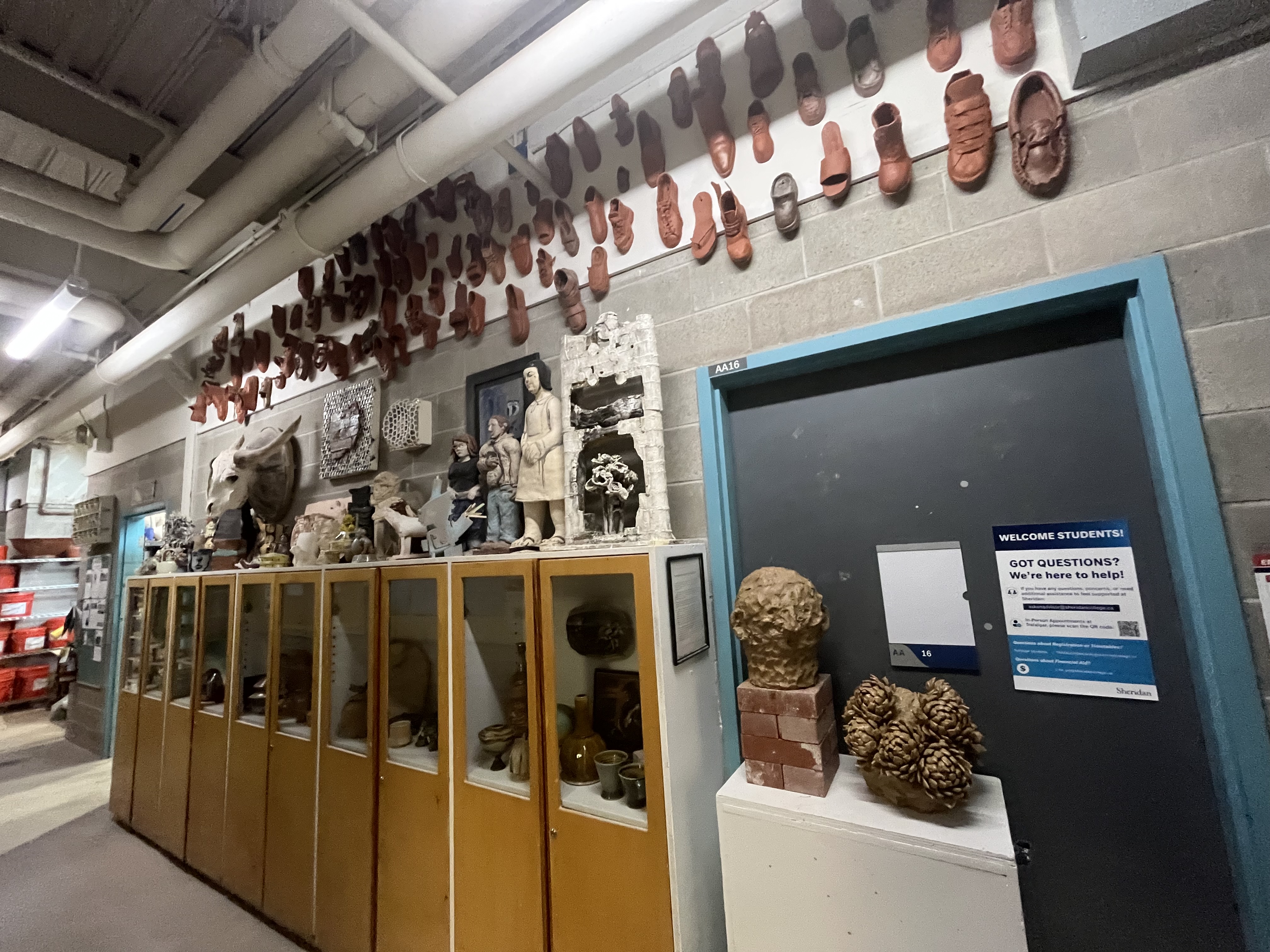 A closer perspective shows the ceramic shoe installation above and a variety of student sculptures arranged along the cabinets and entryway.